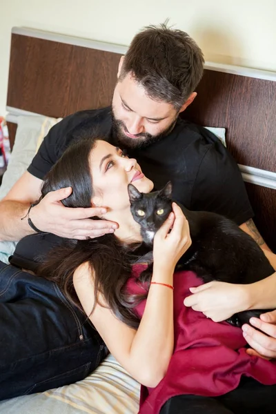 Молодая влюбленная пара на кровати со своими кошками — стоковое фото