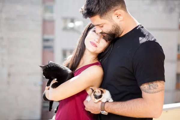 Jovem casal segurando gatos em mãos no terraço — Fotografia de Stock