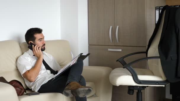 Unavený podnikatel na gauči, mluvit na telefonu — Stock video