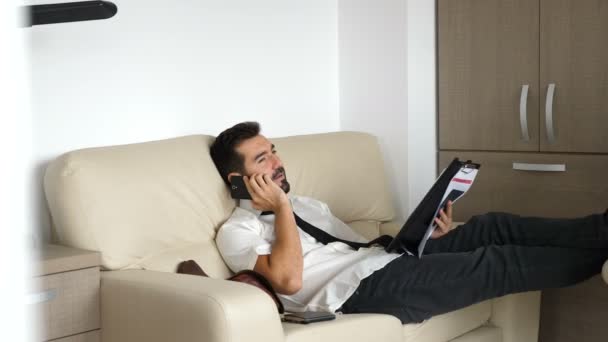 Hombre de negocios cansado en el sofá hablando por teléfono — Vídeo de stock