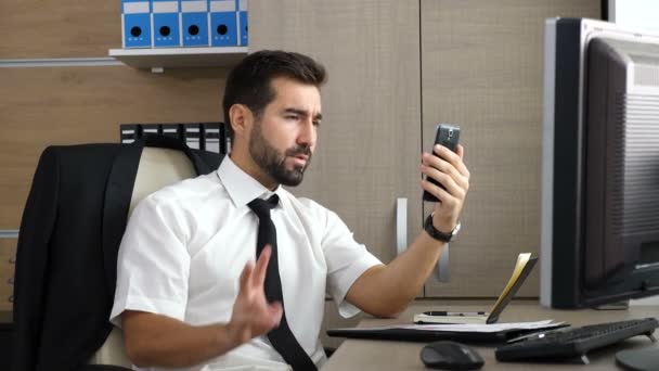Jonge aantrekkelijke zakenman met een video conferentie via zijn telefoon — Stockvideo