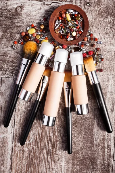 Kosmetikprodukte und Pinsel im konzeptionellen Bild über Holzgrund — Stockfoto