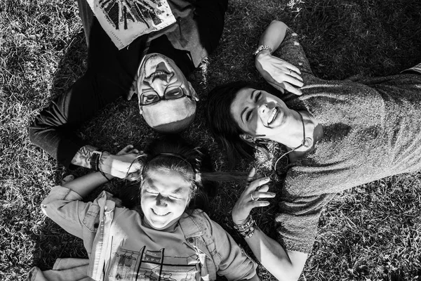 Familia de tres tendidos en el suelo en el parque —  Fotos de Stock
