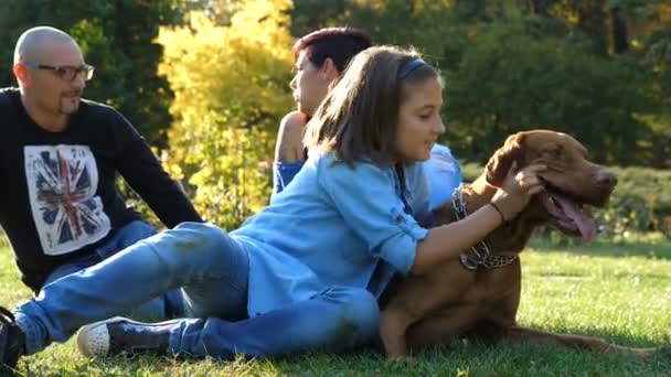 Lycklig familj leker med sin hund i parken — Stockvideo