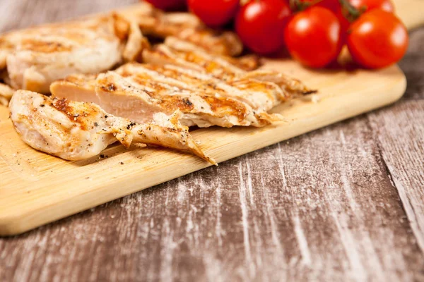 Pechuga de pollo a la parrilla fresca sobre tabla de madera junto a tomates — Foto de Stock