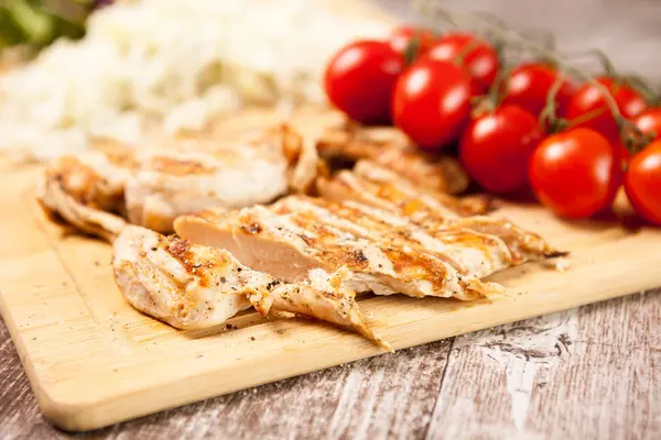 Pechuga de pollo a la parrilla fresca sobre tabla de madera junto a tomates — Foto de Stock