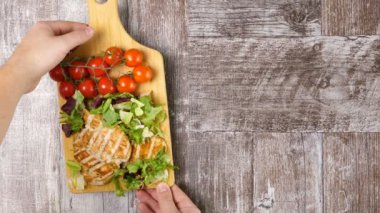 Tavuk, taze kesilmiş salata yaprakları ve domates ahşap tahta üzerinde kavrulmuş