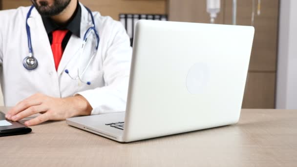 Доктор в своем кабинете за ноутбуком — стоковое видео