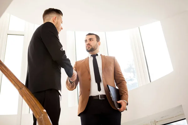 Dois homens de negócios no prédio de escritórios apertando as mãos — Fotografia de Stock