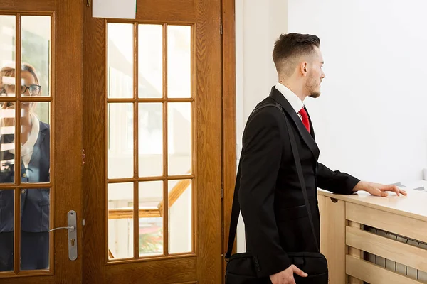 Businessman in office reception area talking with secretary — Stock Photo, Image