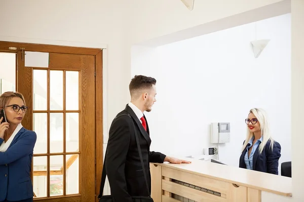 Geschäftsmann im Büro-Empfangsbereich im Gespräch mit Sekretärin — Stockfoto