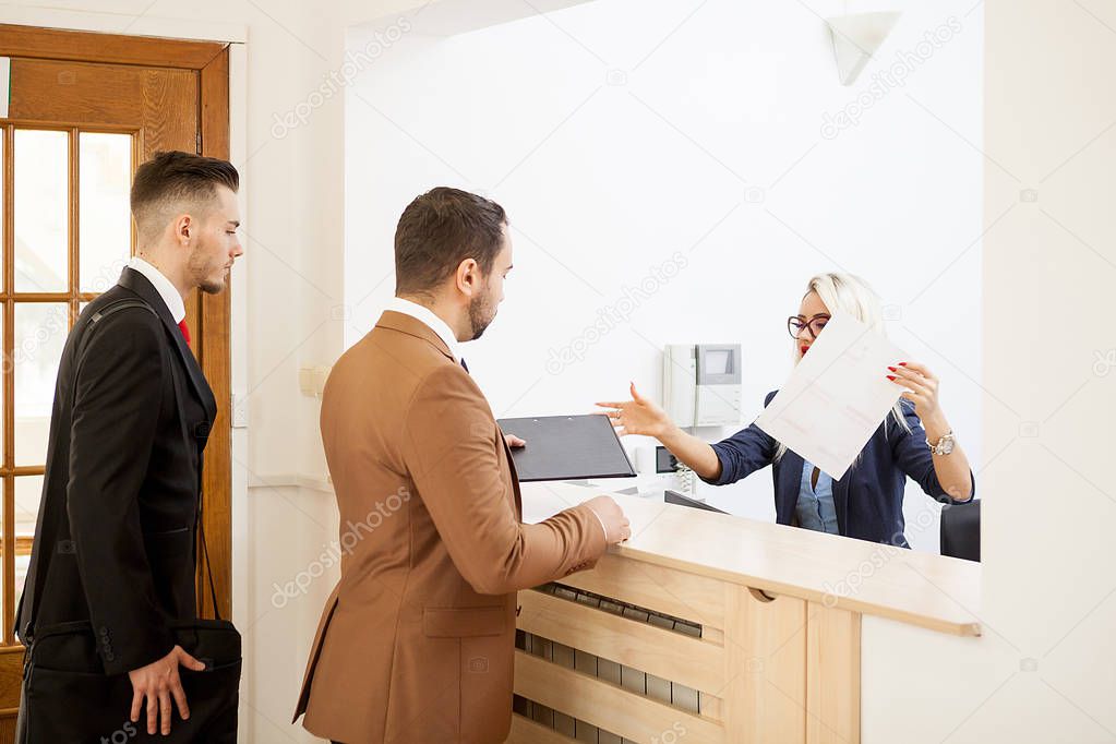 Businessman in office reception area talking with secretary