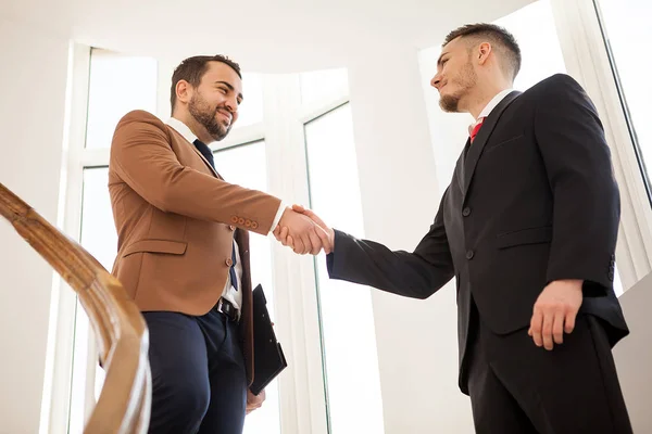 Dois homens de negócios no prédio de escritórios apertando as mãos — Fotografia de Stock