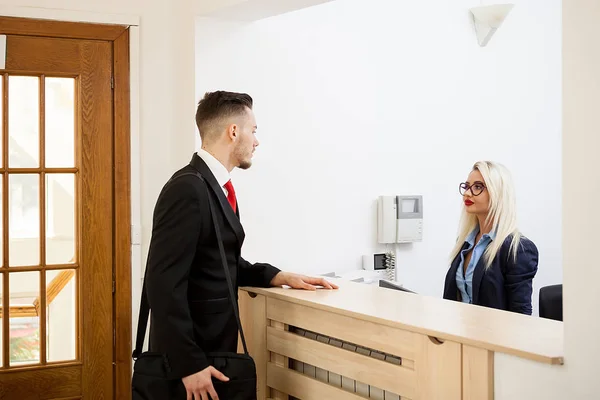 Affärsman i office receptionen talar med sekreterare — Stockfoto