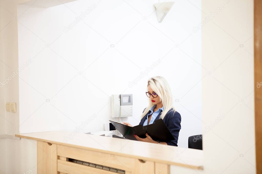 Beautiful blonde secretary looking at folder with documents