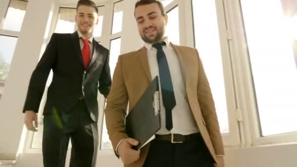 Dos exitosos hombres de negocios subiendo por las escaleras de un edificio de oficinas hablando entre sí — Vídeo de stock