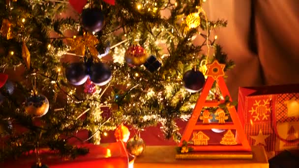 Grúa disparada desde el fondo del árbol de Navidad donde hay cajas de regalo — Vídeos de Stock