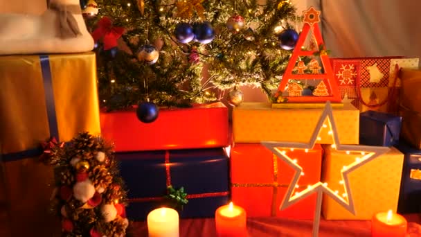 Die Kamera bewegt sich langsam auf den Boden des Weihnachtsbaums zu, wo viele Geschenkboxen platziert sind — Stockvideo