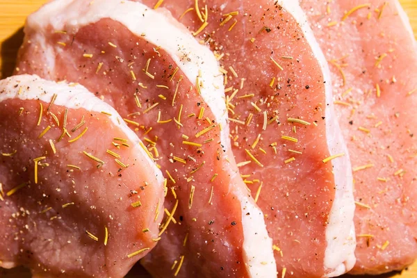 Close-up em carne não cozida temperada com especiarias, sal e pimenta — Fotografia de Stock