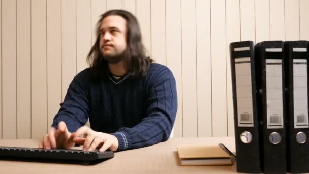 Un hombre de negocios de pelo largo en su oficina está trabajando en una computadora y tiene una crisis de histeria debido a demasiado trabajo. — Vídeo de stock