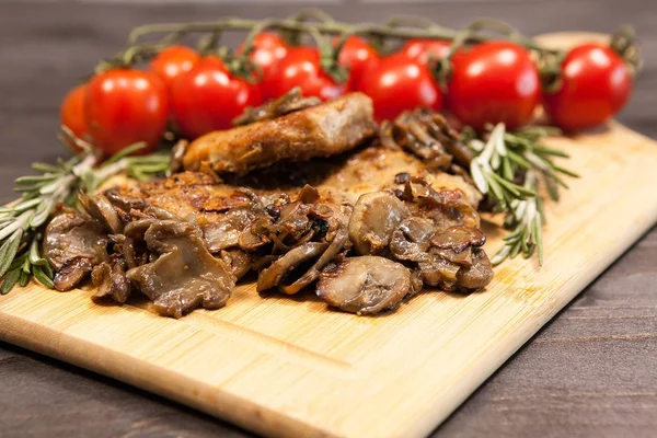 Close up on wooden board with grilled mushrooms and pork steak — Stock Photo, Image