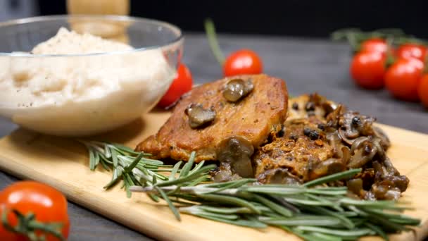 Imágenes de movimiento lento de chuletas de cerdo cocidas con champiñones junto a especias de orégano y tomates cherry — Vídeo de stock