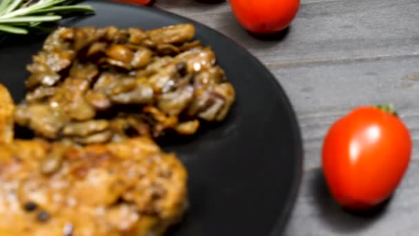 Мясо свинины в тарелке рядом с грибами, орегано, пастой из бобов и помидорами черри — стоковое видео