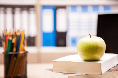 Yığın t yanında bir not defteri ve kalem kitap üzerinde yeşil elma