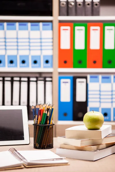 Pomme verte sur pile de livres à côté d'un carnet et crayons sur t — Photo