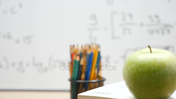 Zooma i fokus spårning tagningar på grönt äpple och färgpennor — Stockvideo