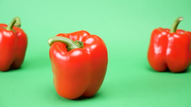 Dolly seguimiento de enfoque en cinco pimientos rojos dulces sobre fondo verde — Vídeos de Stock