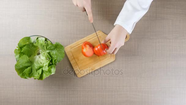 Bovenaanzicht van chef-kok handen snijden tomaten op een houten bord — Stockvideo