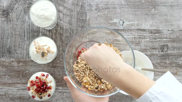 Bovenaanzicht van chef-kok handen voorbereiding muesli met natuurlijke yoghurt en granaatappel — Stockvideo
