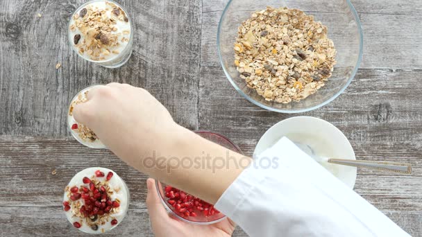 Bovenaanzicht van chef-kok handen voorbereiding muesli met natuurlijke yoghurt en granaatappel — Stockvideo