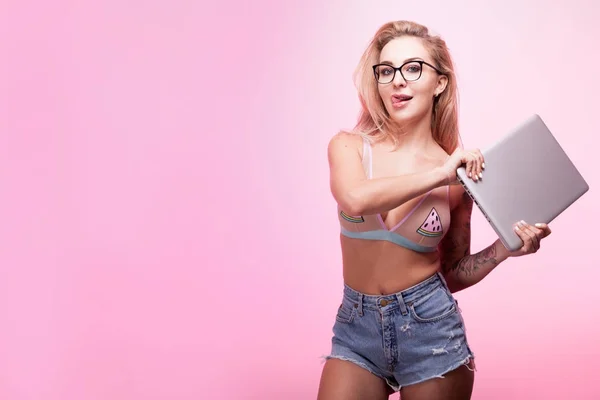 Sexy woman with a laptop in hands on pink background — Stock Photo, Image