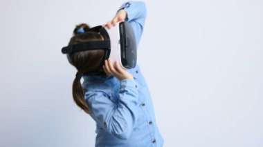 Gri bir arka plan üzerinde VR sanal gerçeklik kulaklık giyen sevimli genç kız