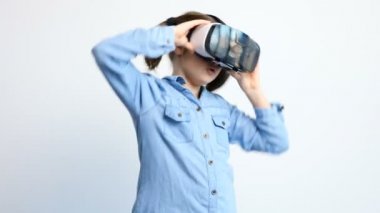 Gri bir arka plan üzerinde VR sanal gerçeklik kulaklık giyen sevimli genç kız