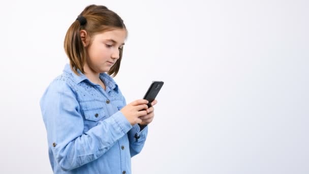 Niña bonita usando teléfono inteligente sobre fondo gris — Vídeos de Stock