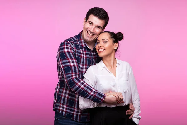 Муж обнимает жену на розовом фоне — стоковое фото