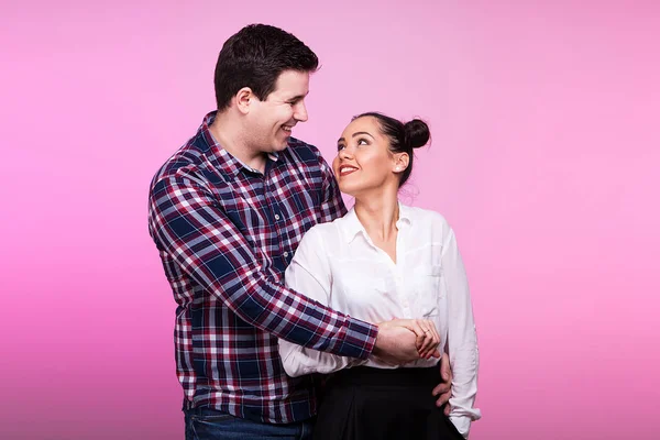 Uomo sorridente che abbraccia una donna su sfondo rosa — Foto Stock