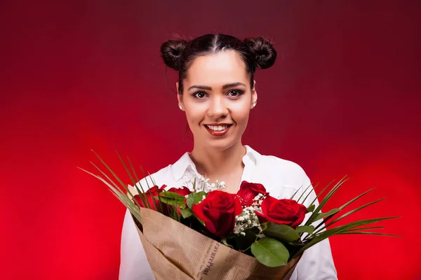 Šťastná žena drží kytici růží v ruce se usmívá na kameru — Stock fotografie
