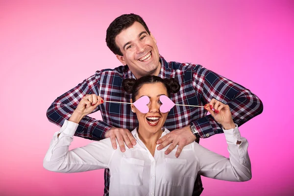 Пара в студии с двумя розовыми сердцами, которые ведут себя глупо — стоковое фото