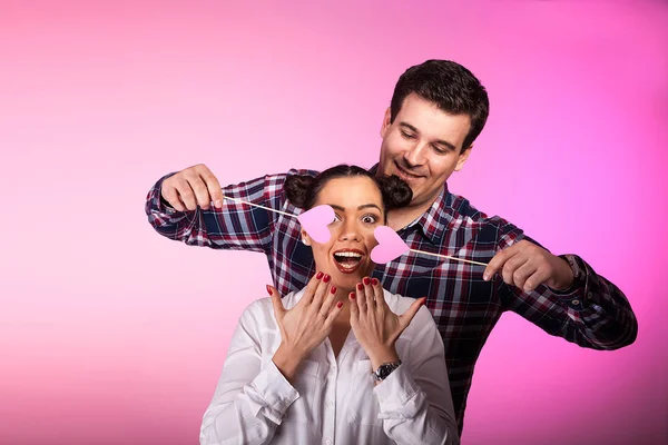 Pareja en estudio con dos corazones rosados siendo tontos — Foto de Stock