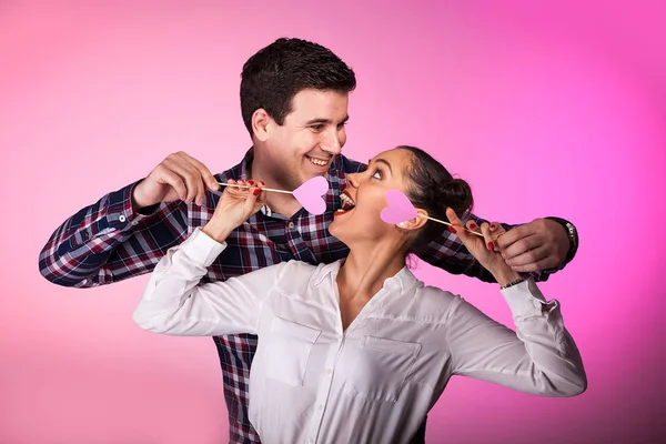 Pareja en estudio con dos corazones rosados siendo tontos — Foto de Stock