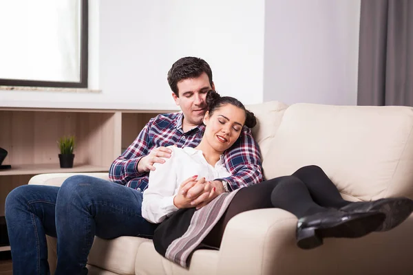 Moglie in suo marito braccia sdraiato sul divano — Foto Stock