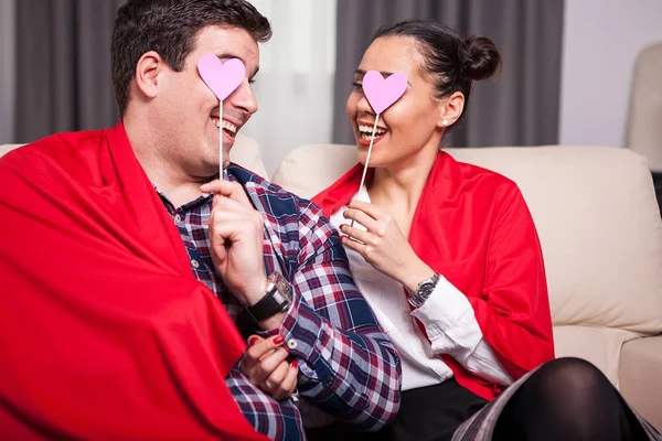 Uomo e donna sorridenti coperti da una coperta rossa — Foto Stock