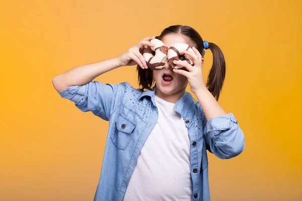 Nettes Mädchen im Studio spielt mit zwei Donuts — Stockfoto