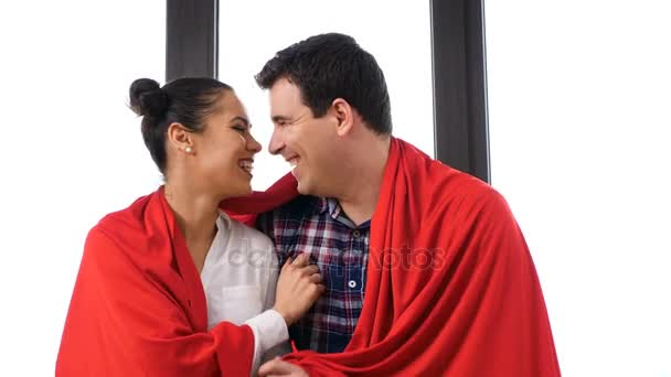 Pareja cubierta con una manta roja junto a una gran ventana — Vídeos de Stock