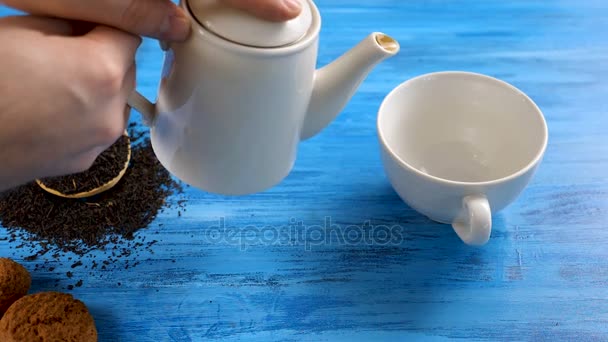 Pouring tea from a kettle in a tea cup — Stock Video