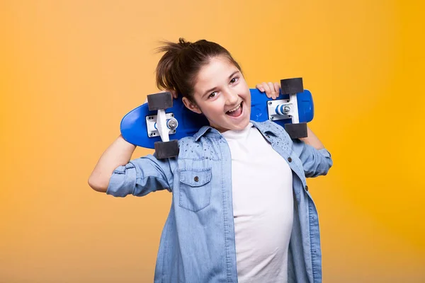 Feliz chica adolescente cool con un monopatín azul en las manos —  Fotos de Stock